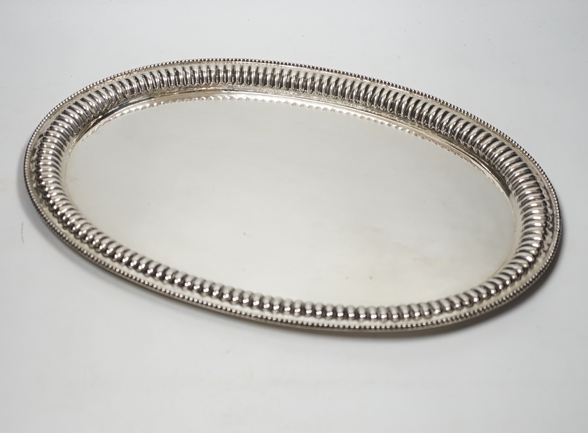 A Far Eastern white metal oval tray, with gadrooned and beaded rim, stamped silver, 45cm